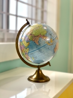 the world globe sitting on a desk next to a window